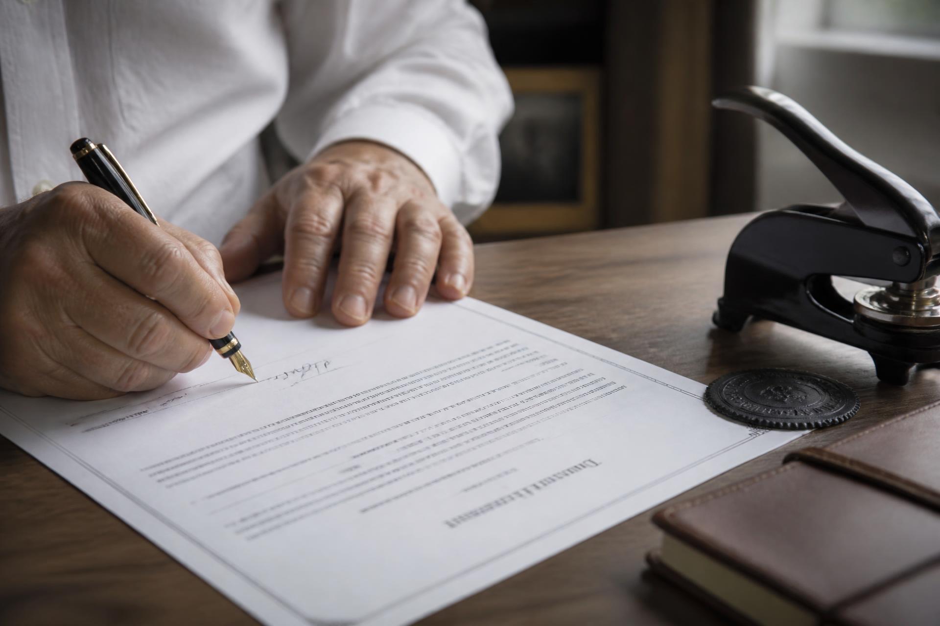 Hands signing a document beside a notary seal and journal
